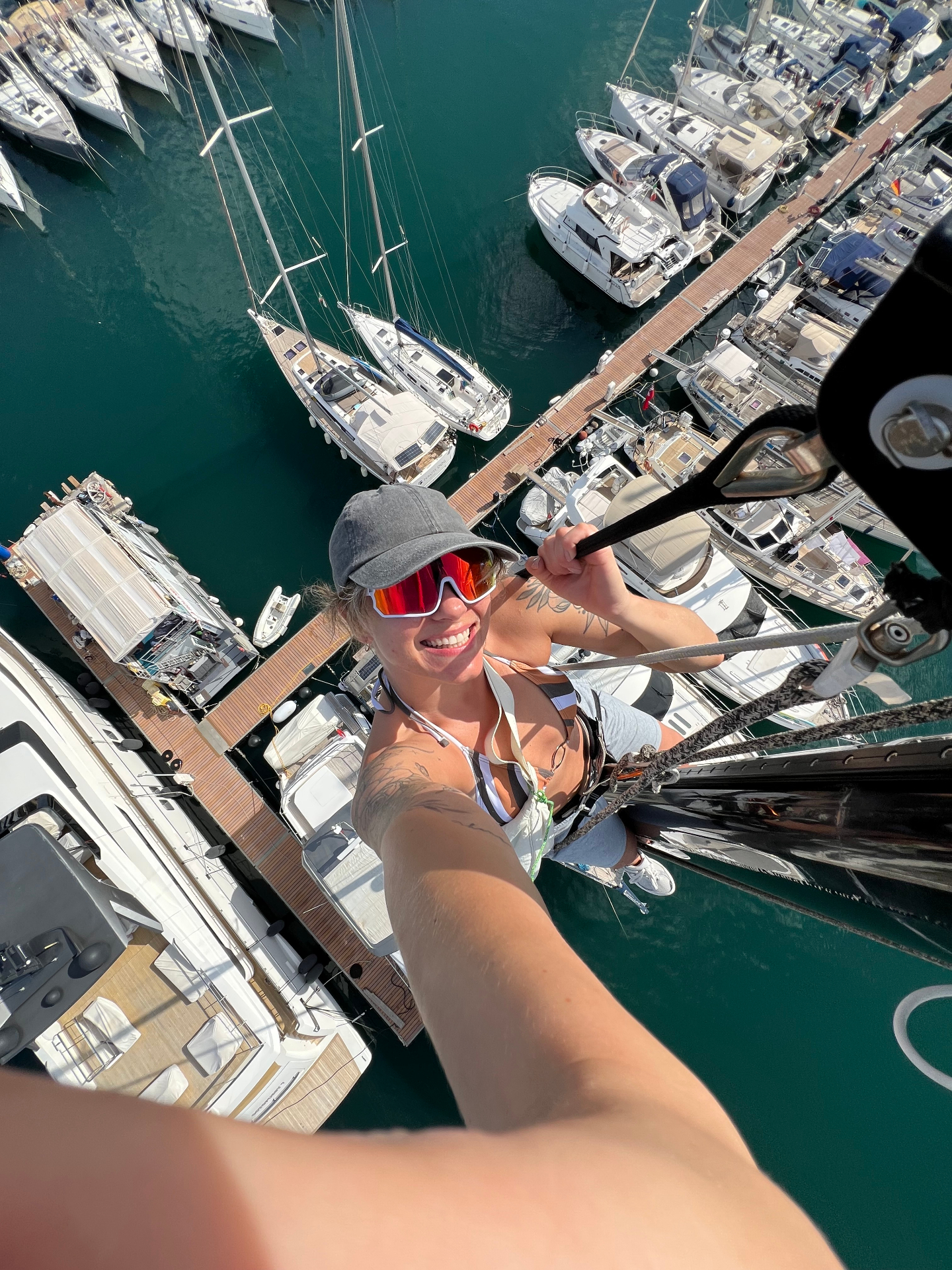 Luiza climbing the mast of a sailing yacht in a marina